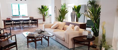 Un salon moderne avec un canapé beige, une table basse en bois et un coin repas comprenant une table et des chaises.