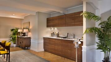 Una cocina moderna con armarios de madera, encimera blanca y zona de comedor con sillas amarillas.