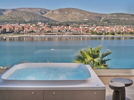 Un jacuzzi con vistas a un pueblo costero y montañas.