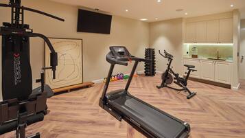 A home gym with a treadmill, stationary bike, and weight machine.