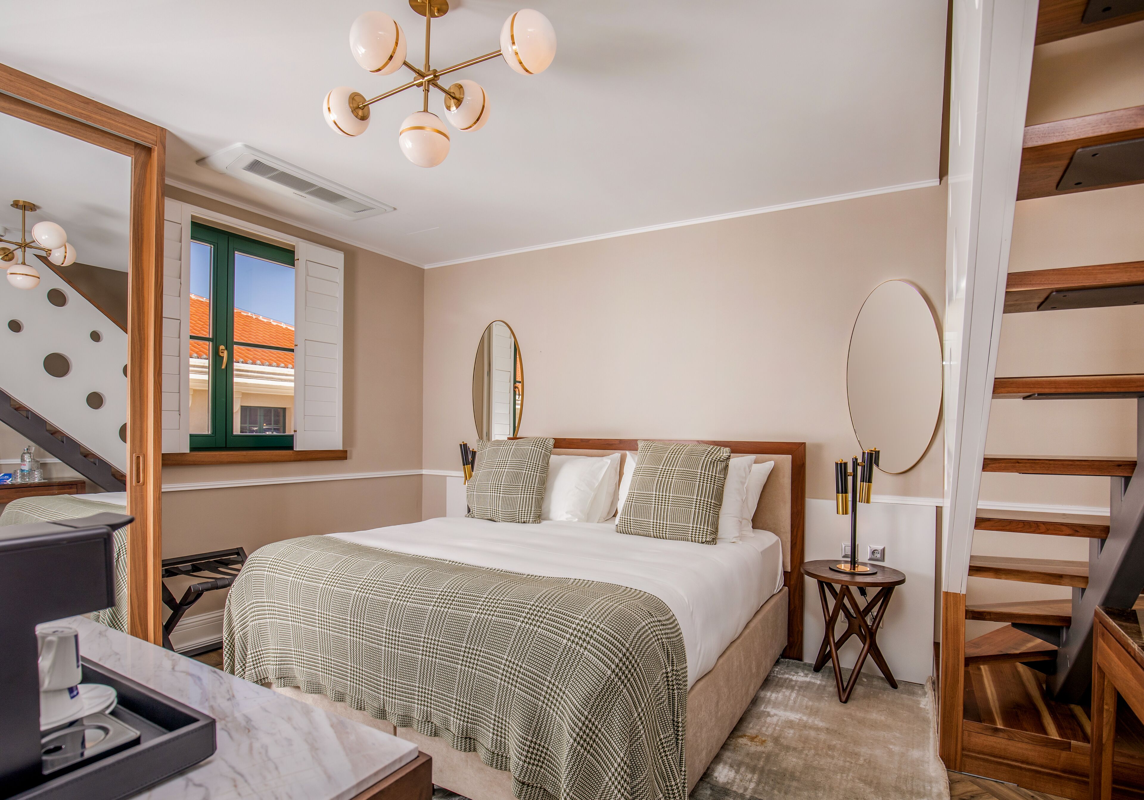 Een hotelkamer met een bed, een bureau met een koffiezetapparaat, een spiegel en een trap.