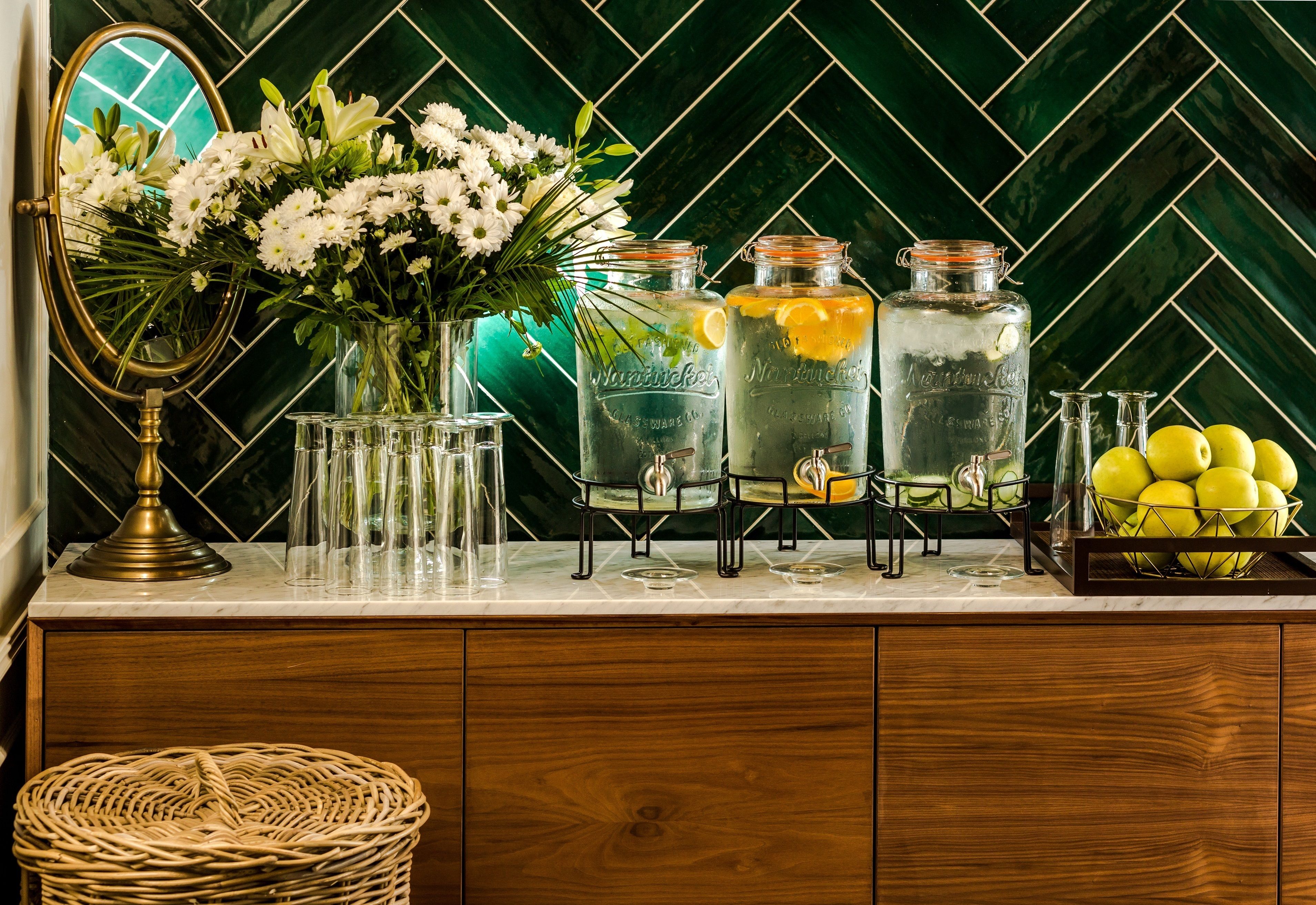 A kitchen counter with a mirror, jars, flowers, and a basket.