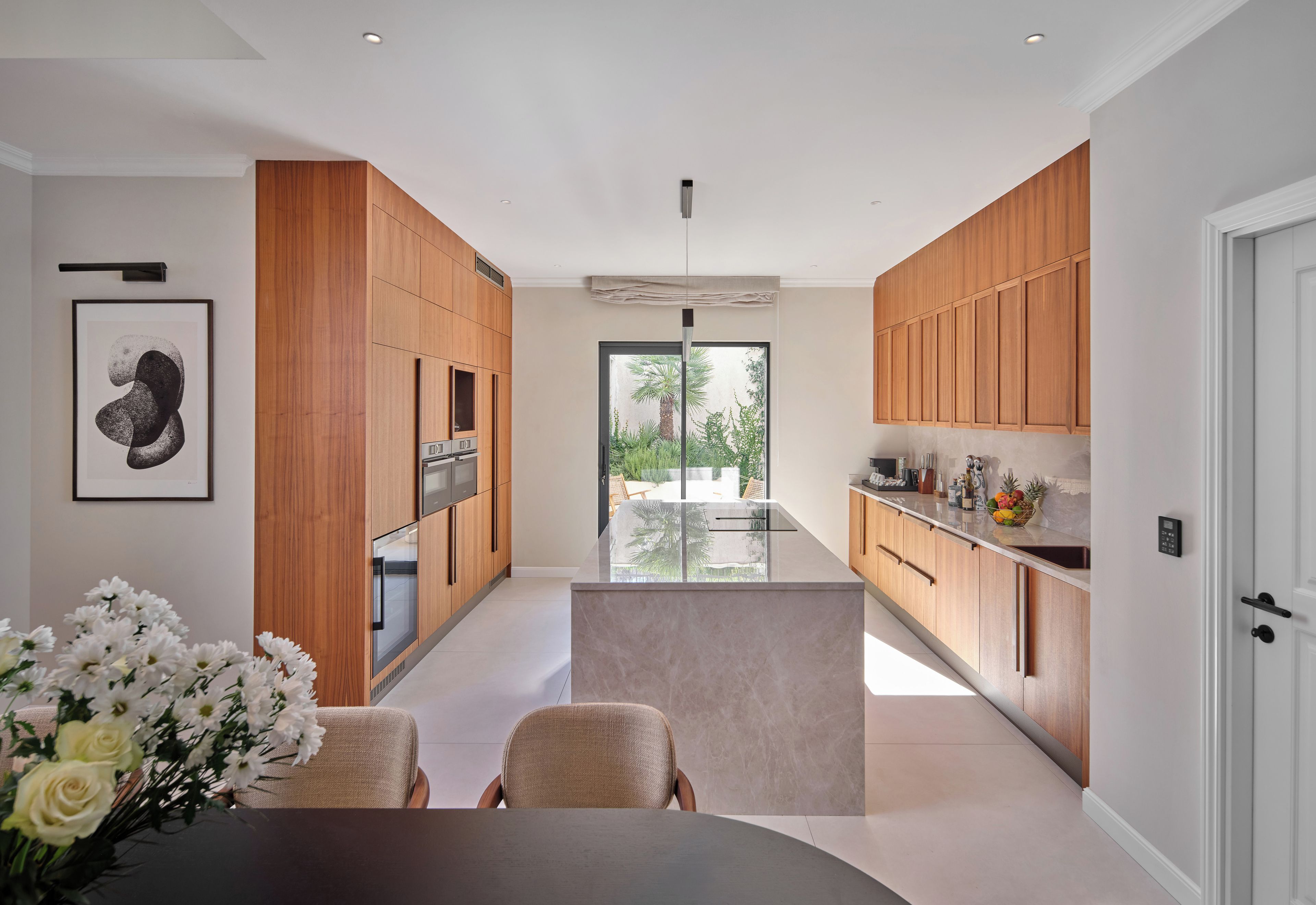 Une cuisine moderne avec des meubles en bois, un îlot central et un coin repas avec des chaises.