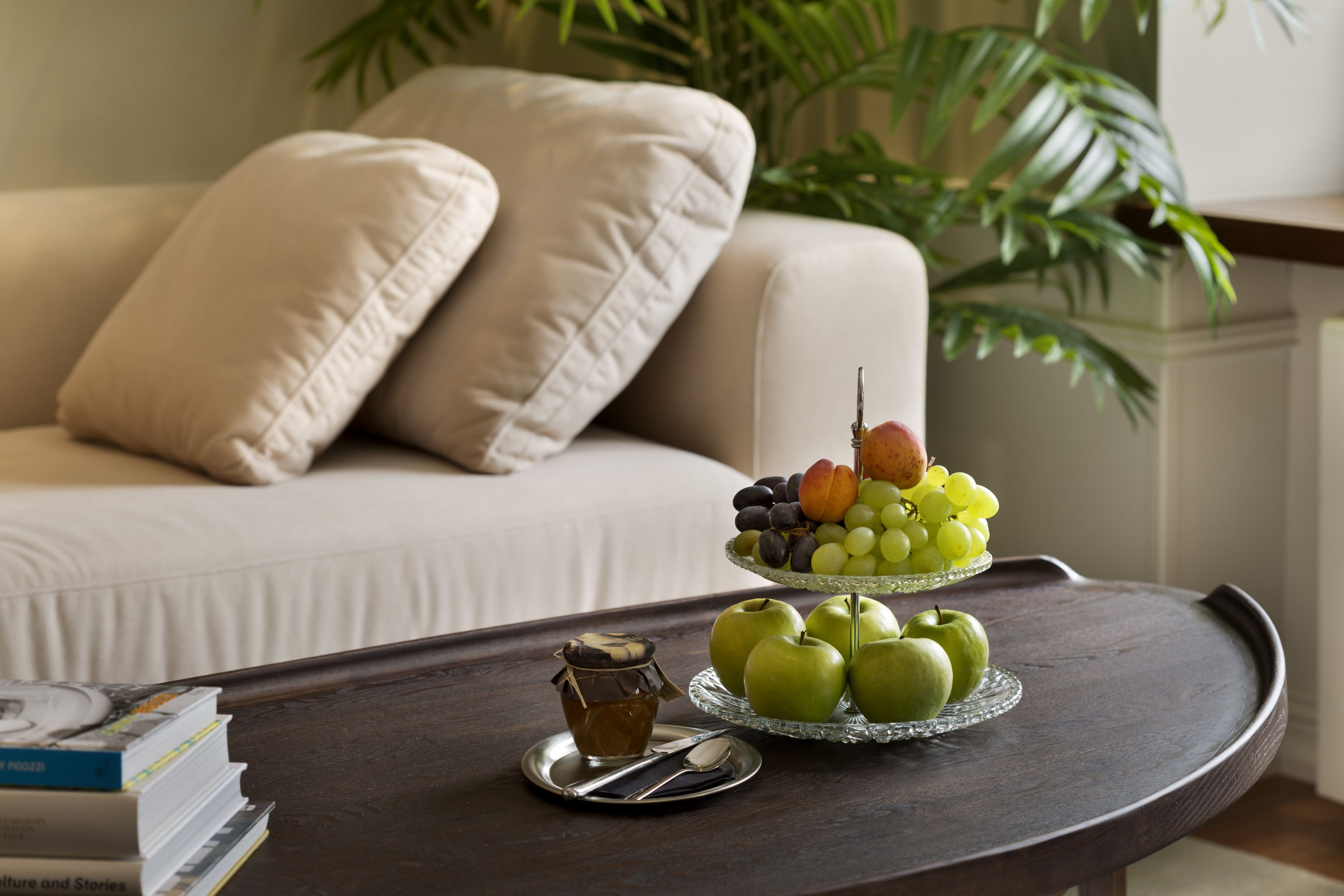 Una mesa de comedor con una bandeja de fruta, un tarro de miel y libros.
