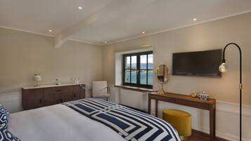 Ein Hotelzimmer mit Bett, Schreibtisch, Stuhl, Fernseher und einem Fenster mit Meerblick.