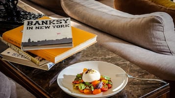 A dining table with a plate of food, a fork, and a stack of books.