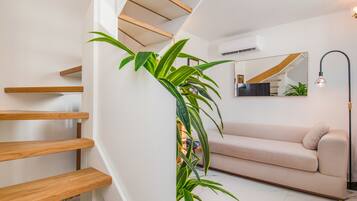Un intérieur moderne avec un escalier, un canapé et un miroir.