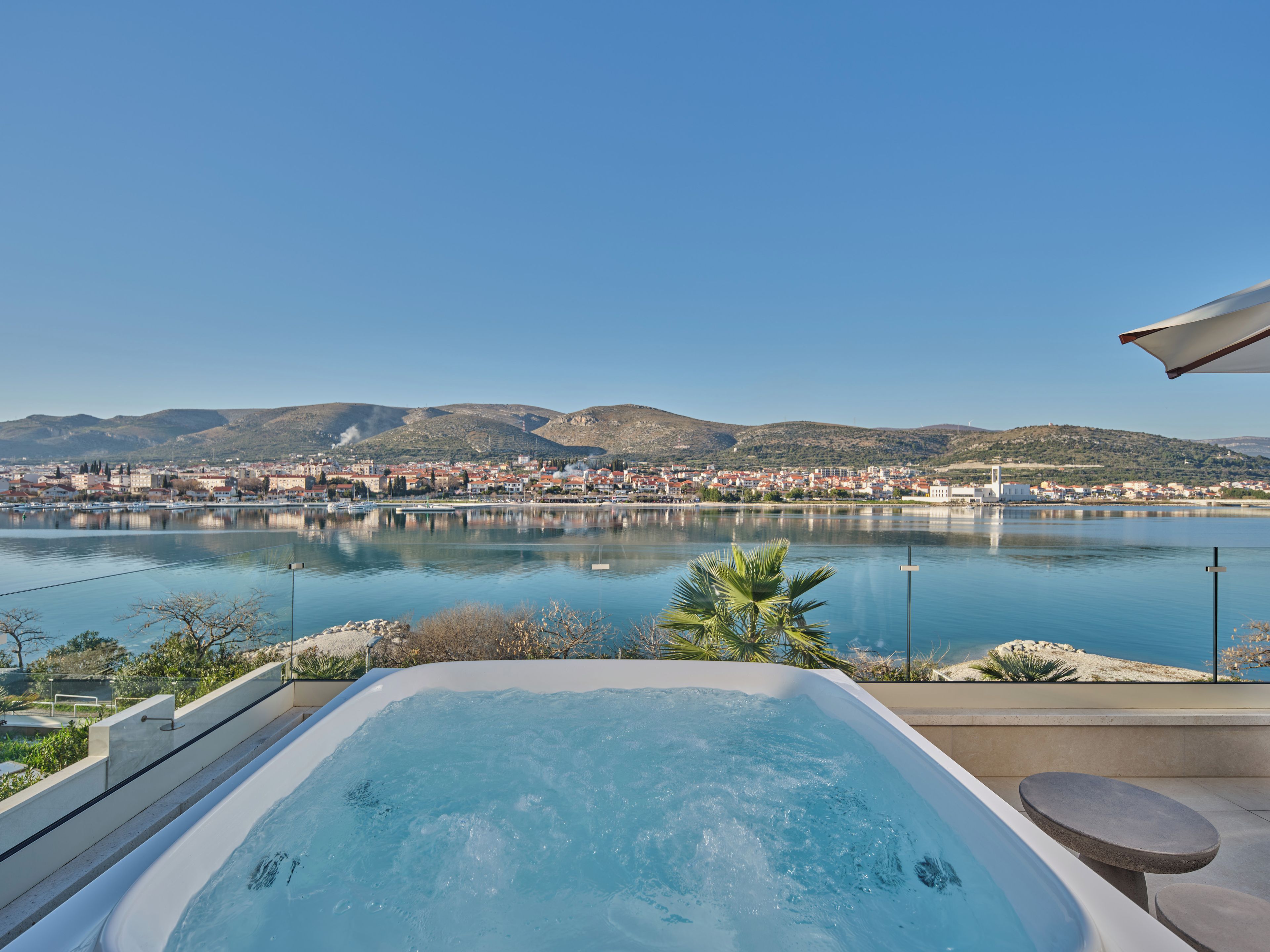 A hot tub with a view of a cityscape and mountains in the background.
