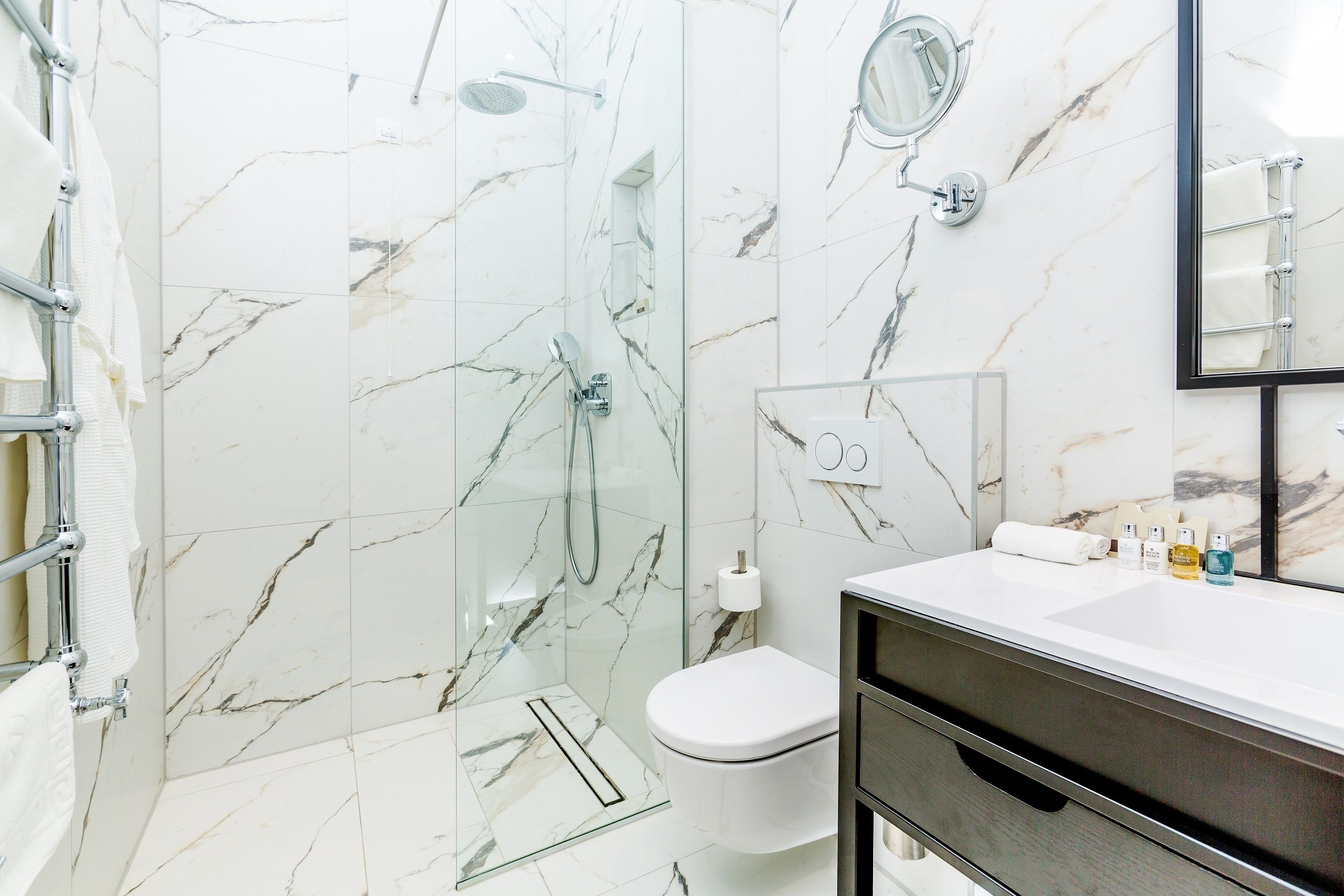 A modern bathroom with a glass-enclosed shower, a toilet, and a vanity with a mirror.