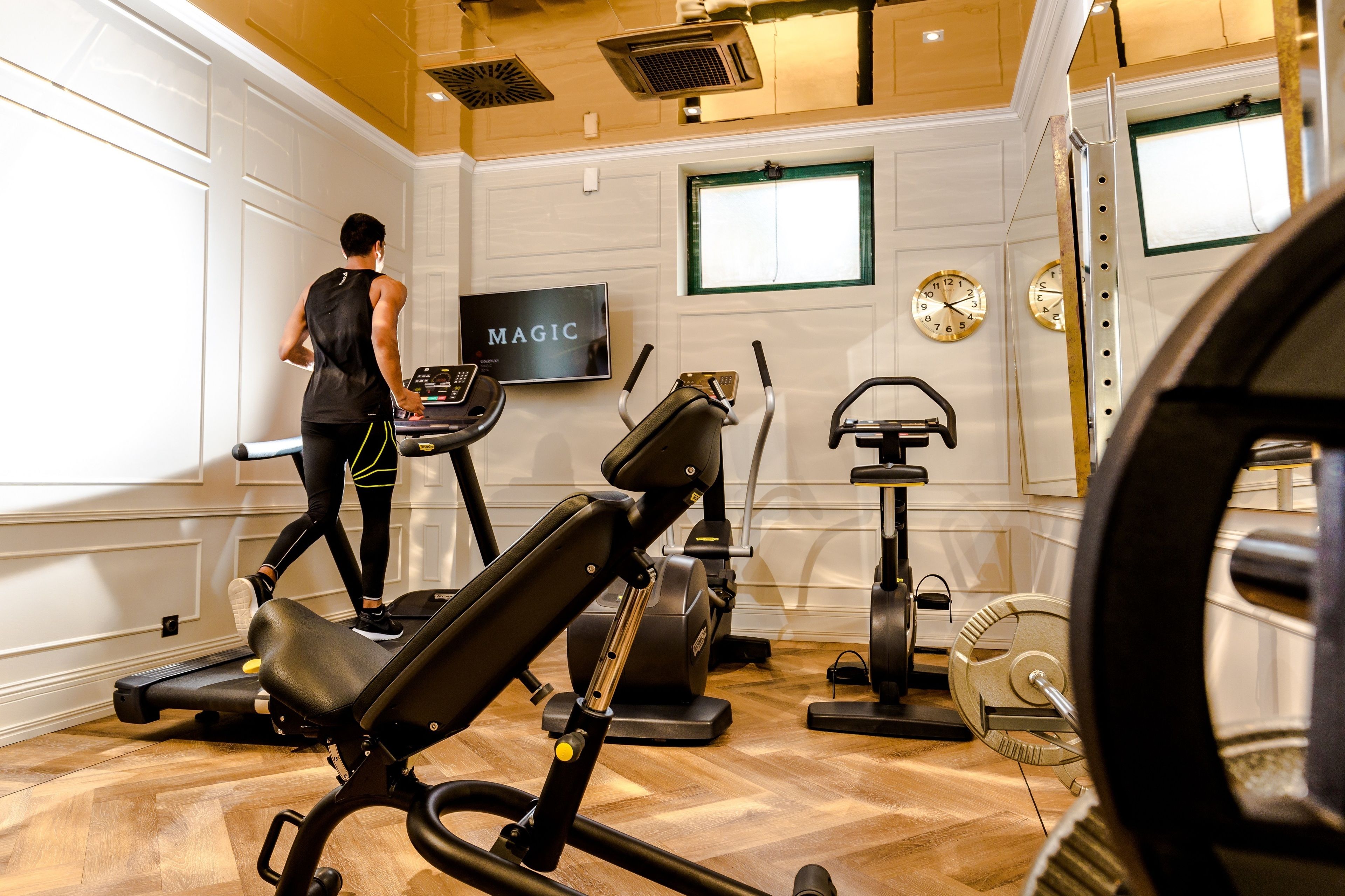 A gym with a treadmill, stationary bikes, and a weight bench.