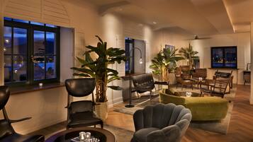 Un salon spacieux avec une grande fenêtre, un canapé vert et plusieurs fauteuils.