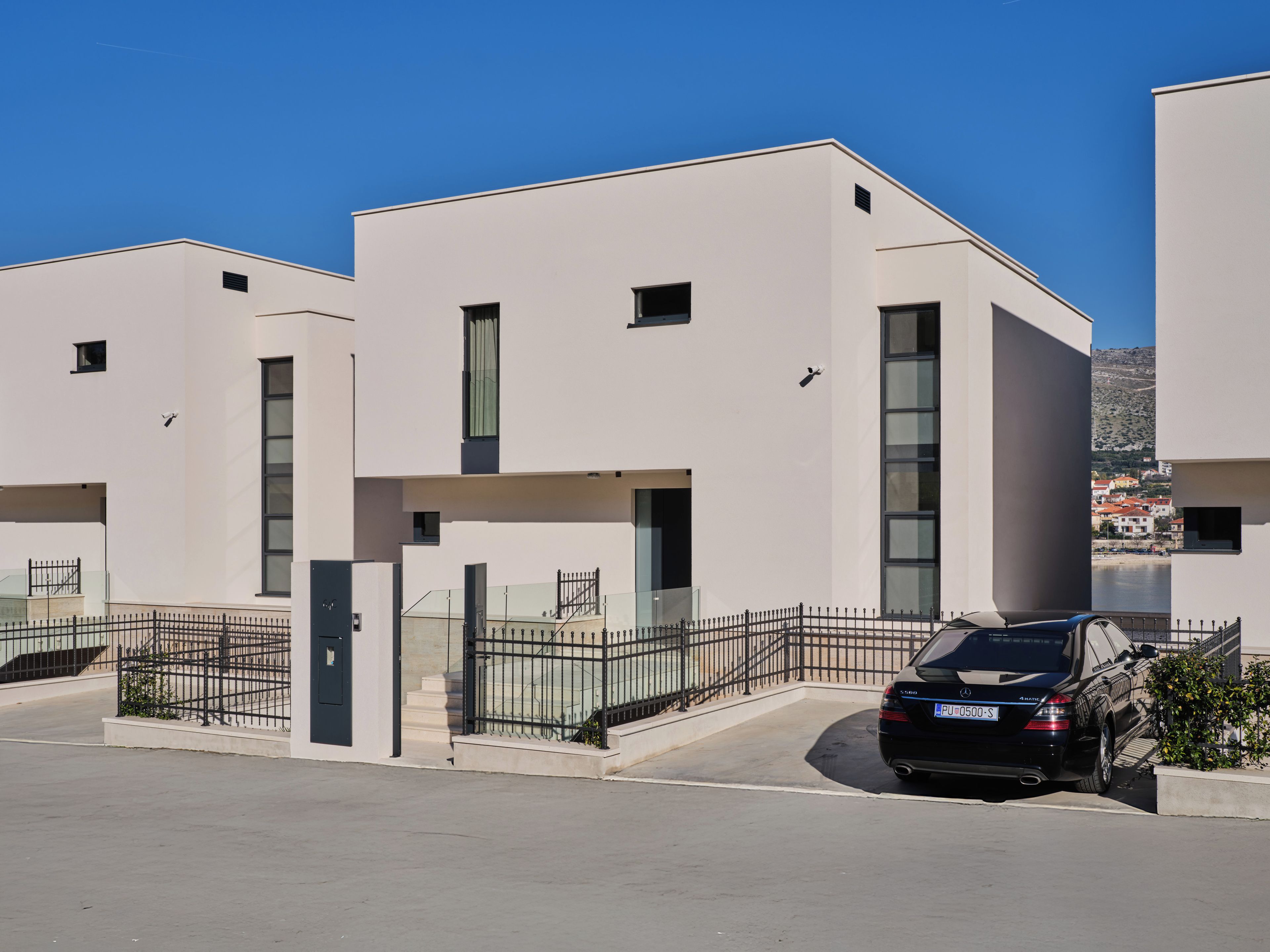Un edificio residencial moderno con un coche estacionado adelante.