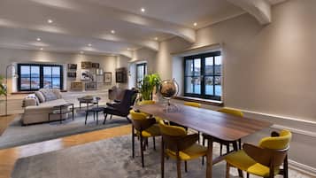 A modern living room with a wooden dining table, yellow chairs, a sofa, and a large window with a view.