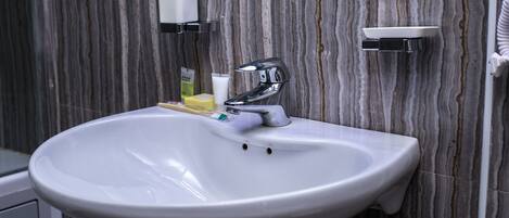 A bathroom with a white sink, chrome faucet, and marble-patterned walls.