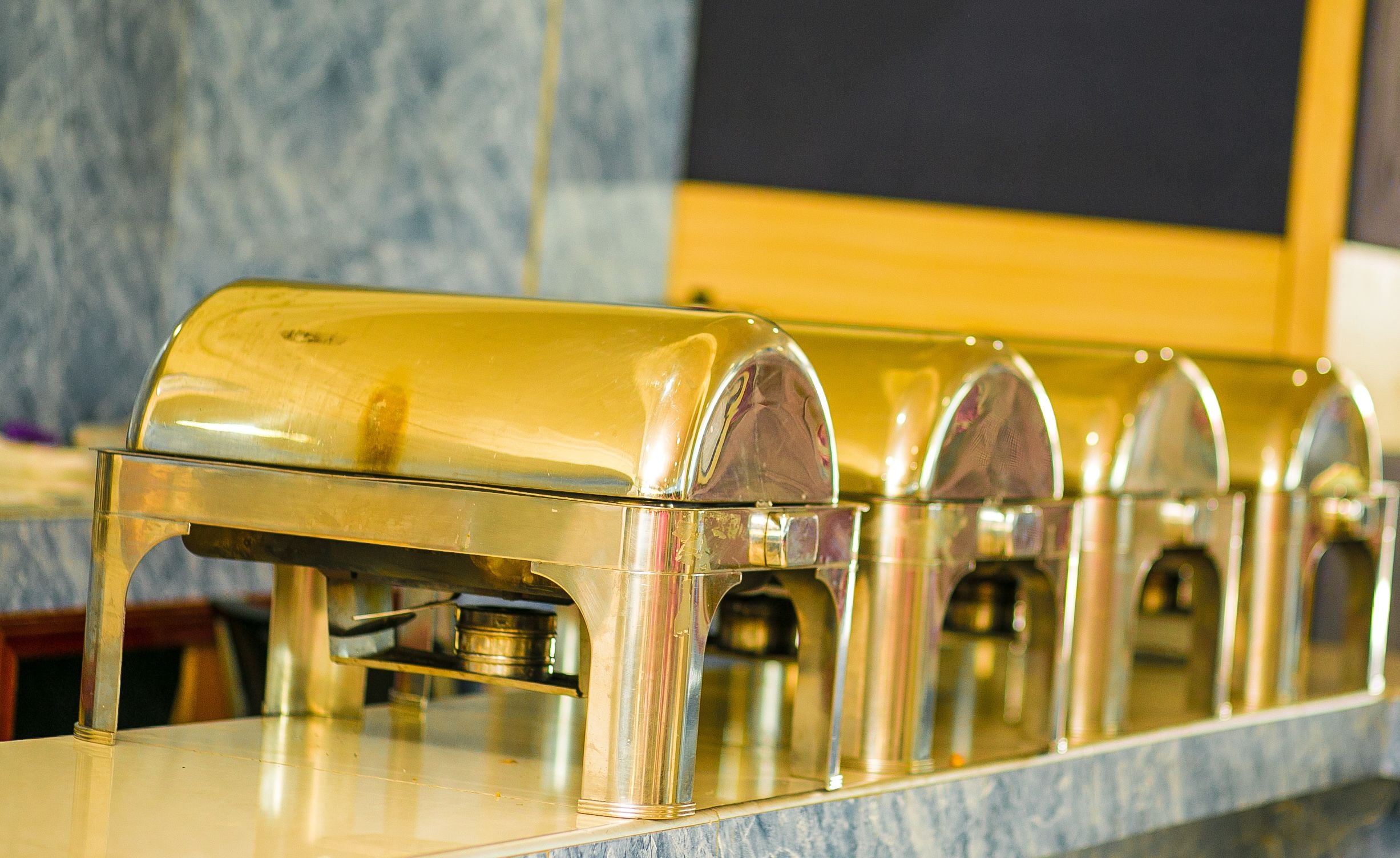 A row of clear, metallic, arched dispensers on a marble countertop.