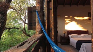 Eine Holzhütte mit einem Bett, einem Nachttisch und einem Fenster.