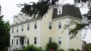 A two-story building with a symmetrical facade, a central entrance with a staircase, and a small porch. - DesBarres Manor Inn (Guysborough)