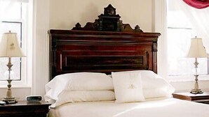A neatly made bed with white linens, a wooden headboard, and two bedside lamps. - DesBarres Manor Inn (Guysborough)