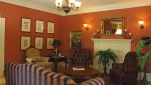 A living room with a fireplace, striped sofa, armchairs, and wall-mounted lamps. - DesBarres Manor Inn (Guysborough)