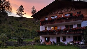 A multi-story building with balconies, a grassy lawn, and a hilly backdrop. - Das Habitat (Leutasch)