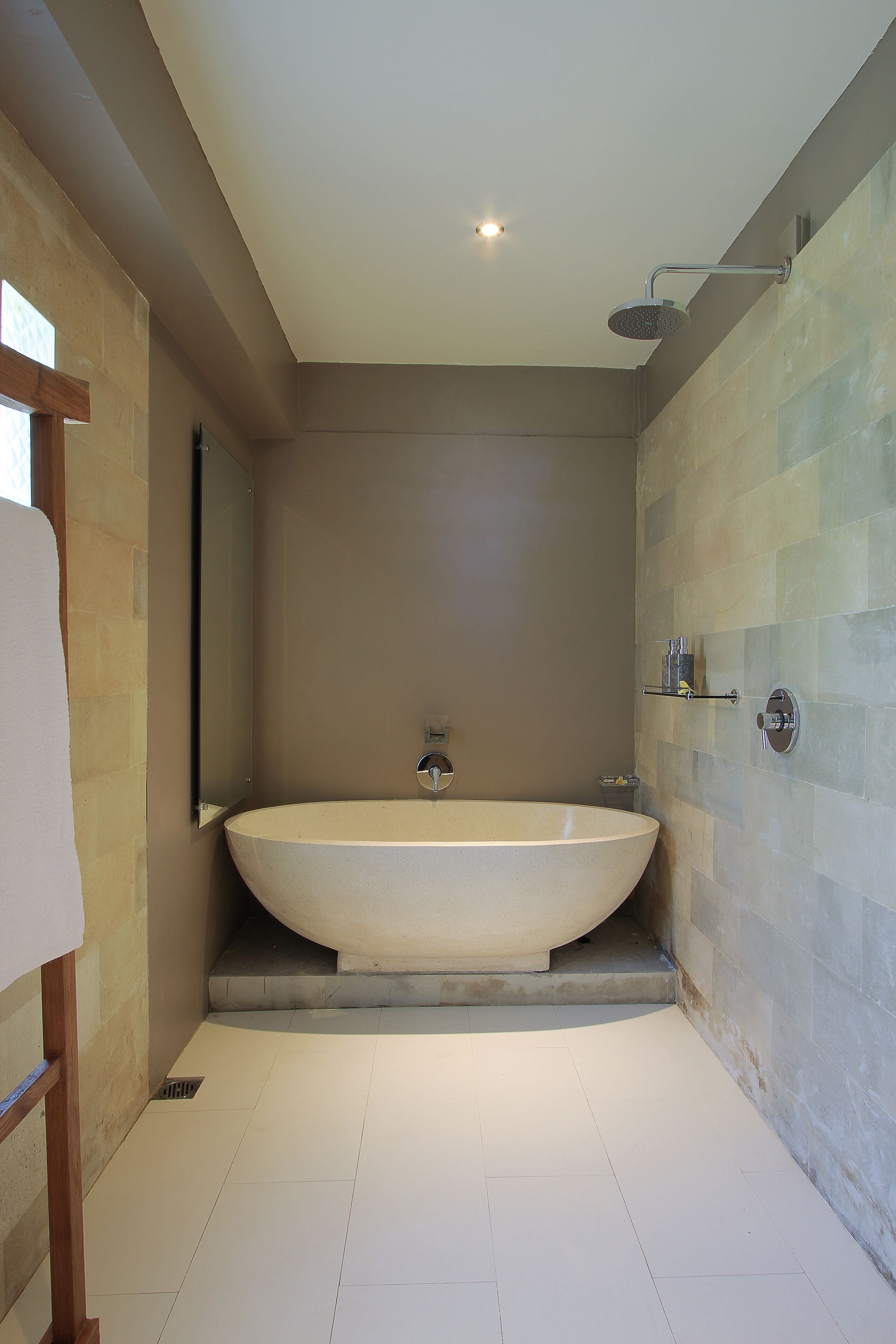 Un baño moderno con una bañera independiente, un cabezal de ducha y un espejo.