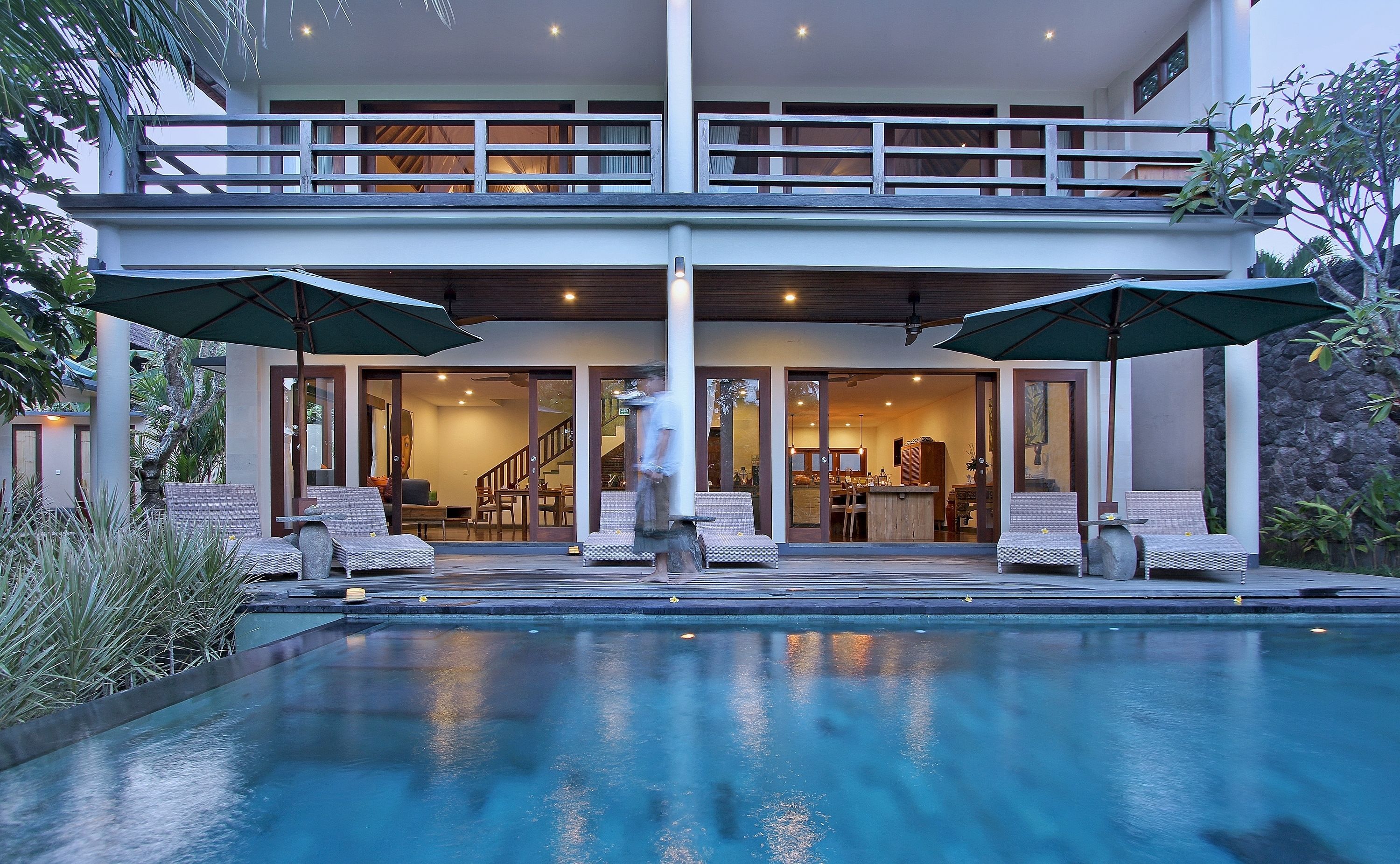 Une maison à deux étages dotée d’une piscine, d’un espace salon extérieur et d’un escalier menant à l’étage supérieur.