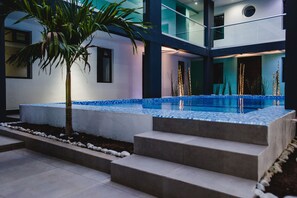 A modern outdoor pool area with a palm tree, steps leading to the pool, and a geometric tiled design. - Hotel Flamingo (Mérida)