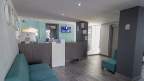 A reception area with a desk, a television, and seating. - Hotel Flamingo (Mérida)