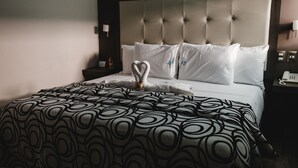 A hotel room with a tufted headboard, white bedding, and a patterned throw blanket. - Hotel Flamingo (Mérida)