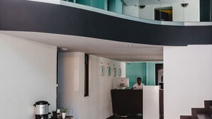 A modern hotel lobby with a high ceiling, a staircase, and a reception desk. - Hotel Flamingo (Mérida)