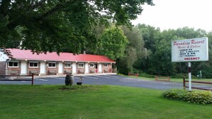 A motel with a red roof and a signboard listing amenities like cable TV, WIFI, BBQ pits, heat & air, and pet-friendly policy. - Paradise Resort and Cabins (Gansevoort)