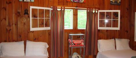A cabin with two beds, wooden walls, and dog-themed artwork.