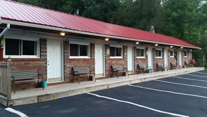 A motel with a red roof, numbered rooms, and outdoor seating. - Paradise Resort and Cabins (Gansevoort)