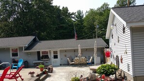 A house with a covered porch, outdoor seating, and a small garden area. - Paradise Resort and Cabins (Gansevoort)