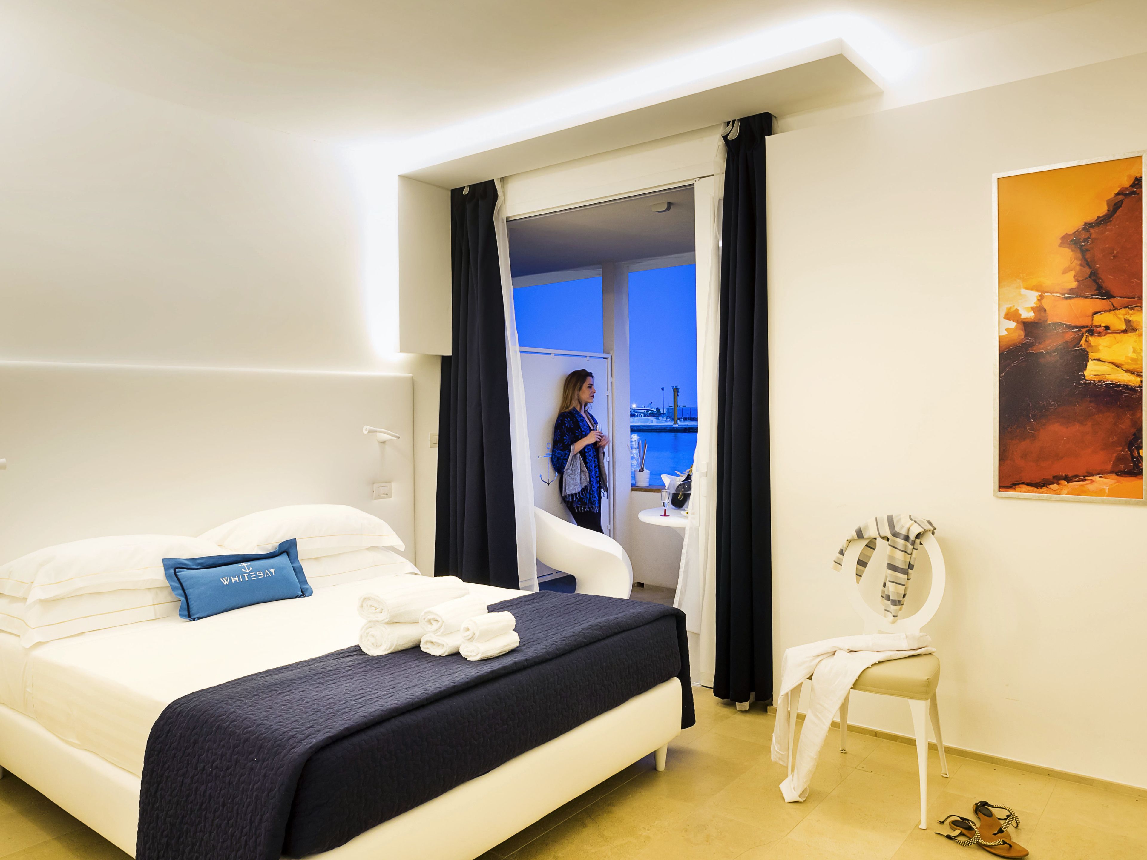 Una habitación de hotel con una cama, una silla, una mesa y un cuadro en la pared.