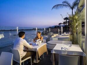 A couple dining at an outdoor table with a view of the sea. - White Bay Resort (Syracuse)