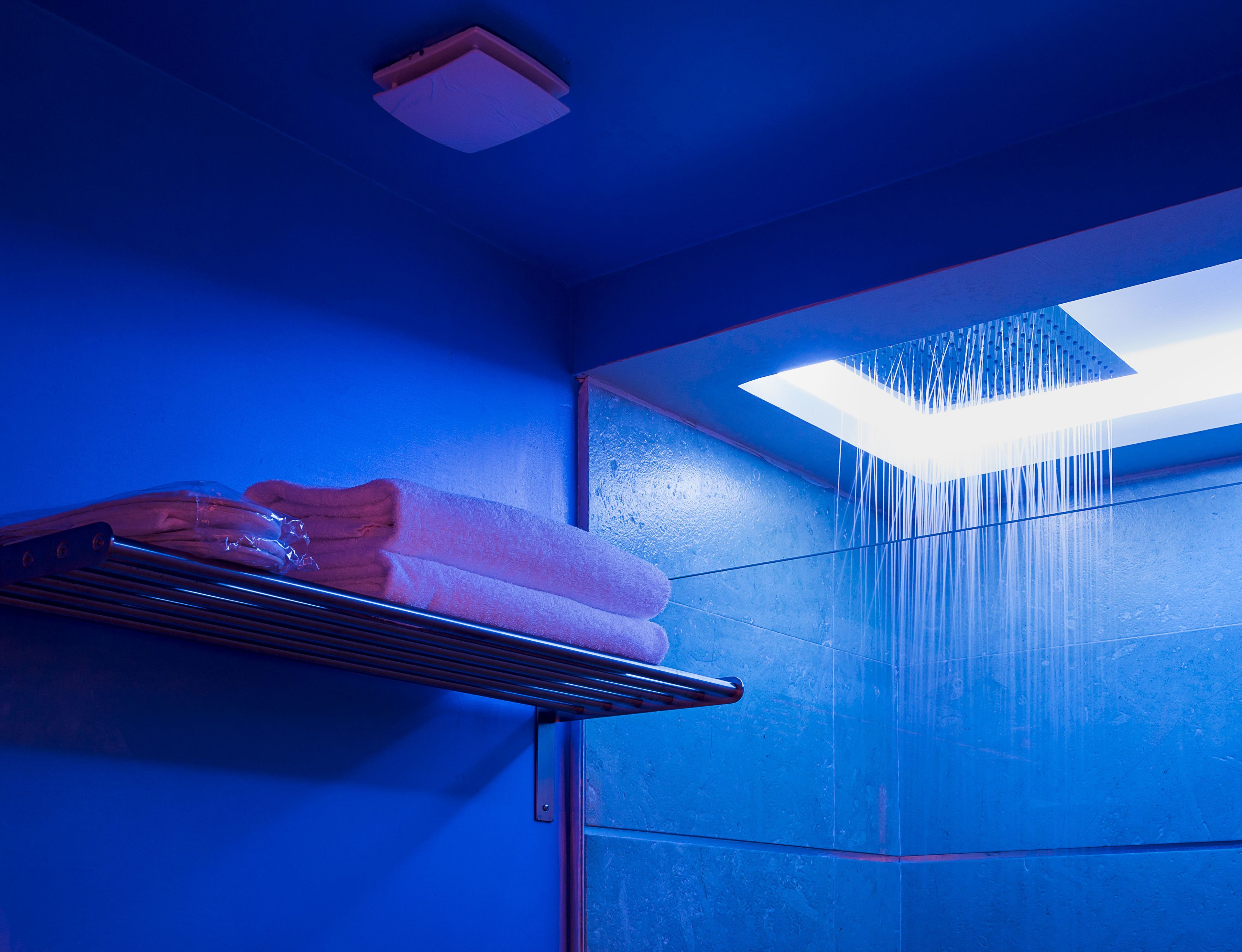 Ein Badezimmer mit blauer Wand, einer Duschbrause und einem Handtuchhalter.