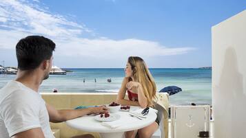 Una pareja cenando en una mesa con vista al mar y a los barcos.