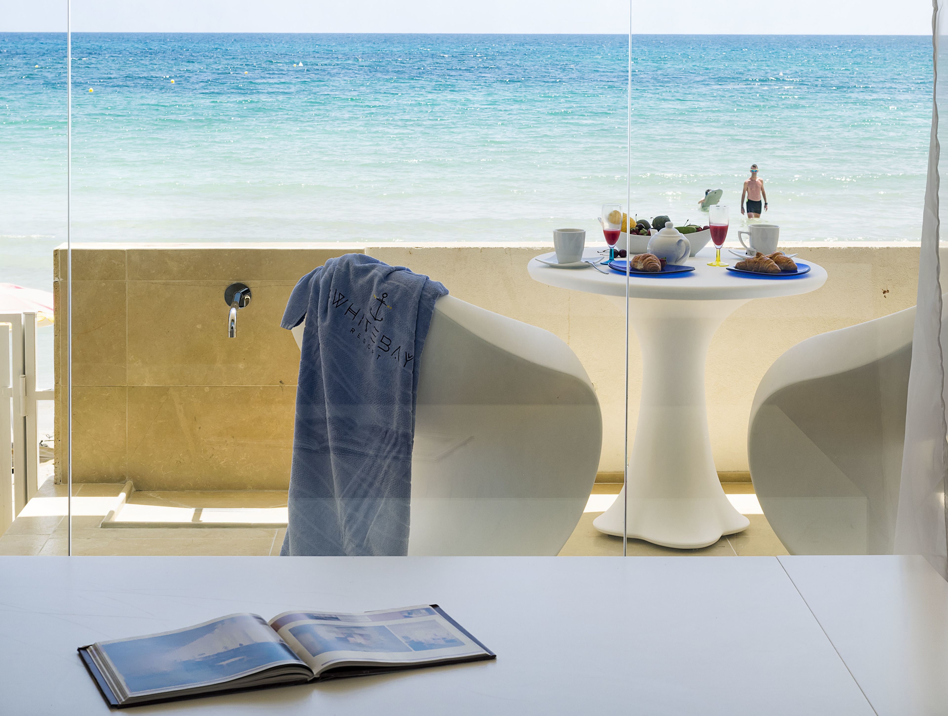Ein Zimmer mit Meerblick, ein Tisch mit Frühstücksangeboten und ein Handtuch an der Wand.