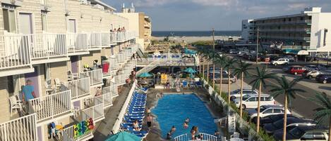 A hotel with a swimming pool, multiple balconies, and a view of the ocean.