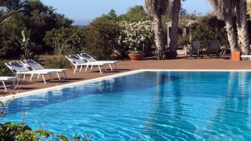 Piscina all'aperto, una piscina a sfioro, lettini