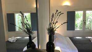 Habitación de hotel con cama, mesita de noche, lámpara y dos jarrones con plantas.