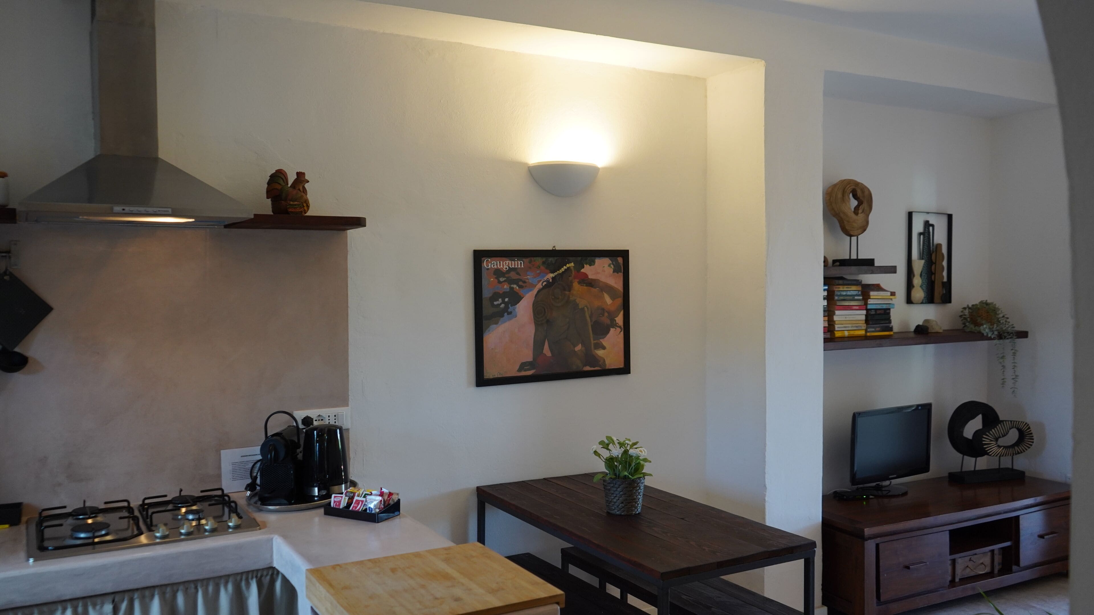 Una cucina moderna con piano cottura a gas, macchina per il caffè e un piccolo tavolo da pranzo.