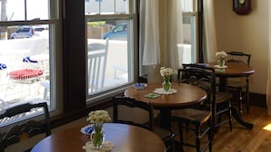 Un coin repas avec une table et des chaises en bois, un vase rempli de fleurs et une horloge fixée au mur.