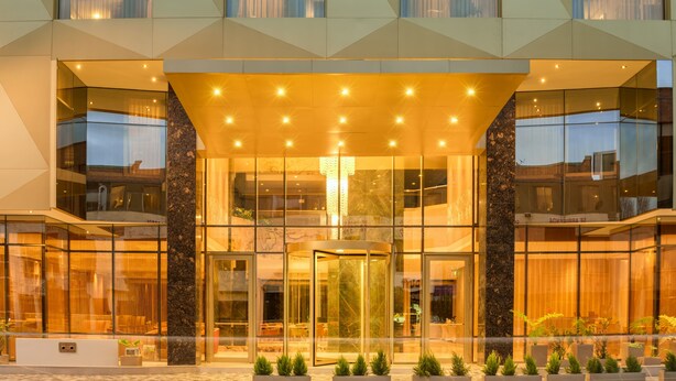 A modern hotel entrance with a revolving door, glass facade, and a geometric pattern on the upper level. - Hotel El Dorado Bogota (Bogotá)