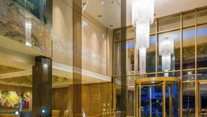 A spacious lobby with a marble floor, a glass elevator, and a seating area with chairs. - Hotel El Dorado Bogota (Bogotá)