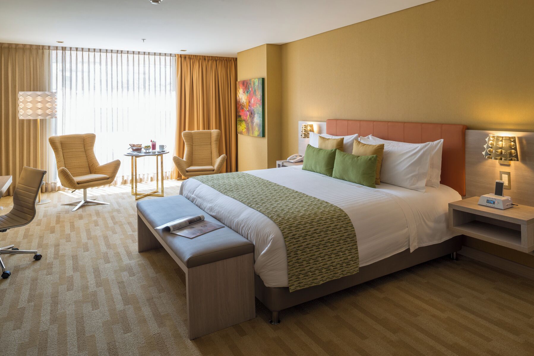 Une chambre d’hôtel avec un grand lit, un bureau, une chaise et une petite table.