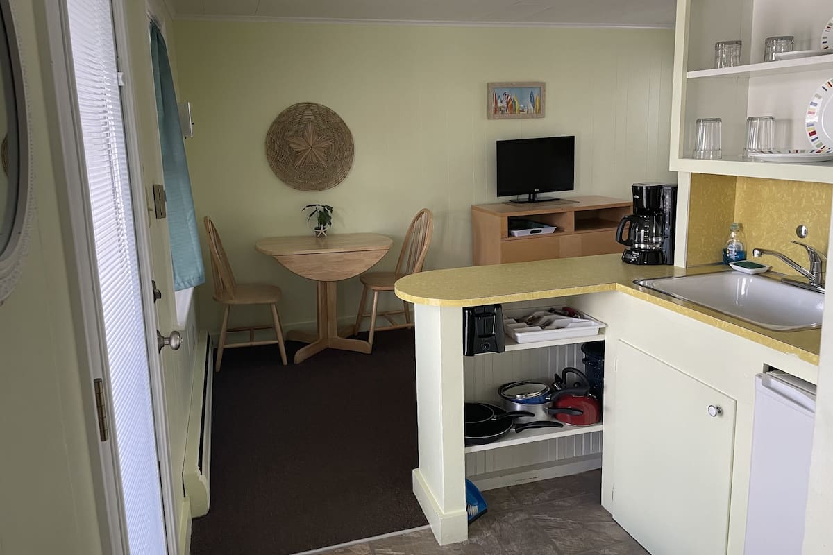 A compact kitchen with a dining area, a television, and a coffee maker.