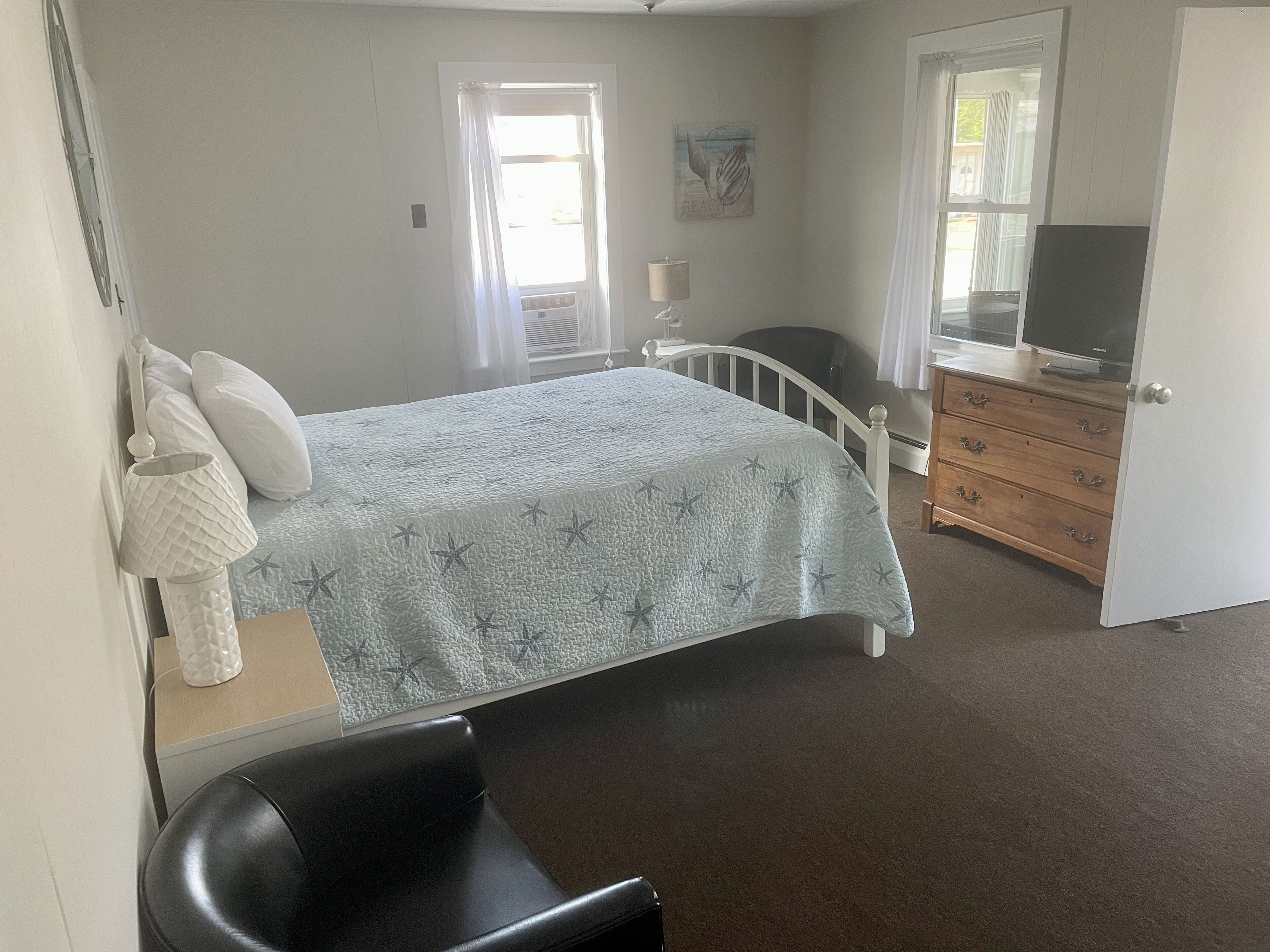 A bedroom with a bed, a dresser, a chair, and a television.