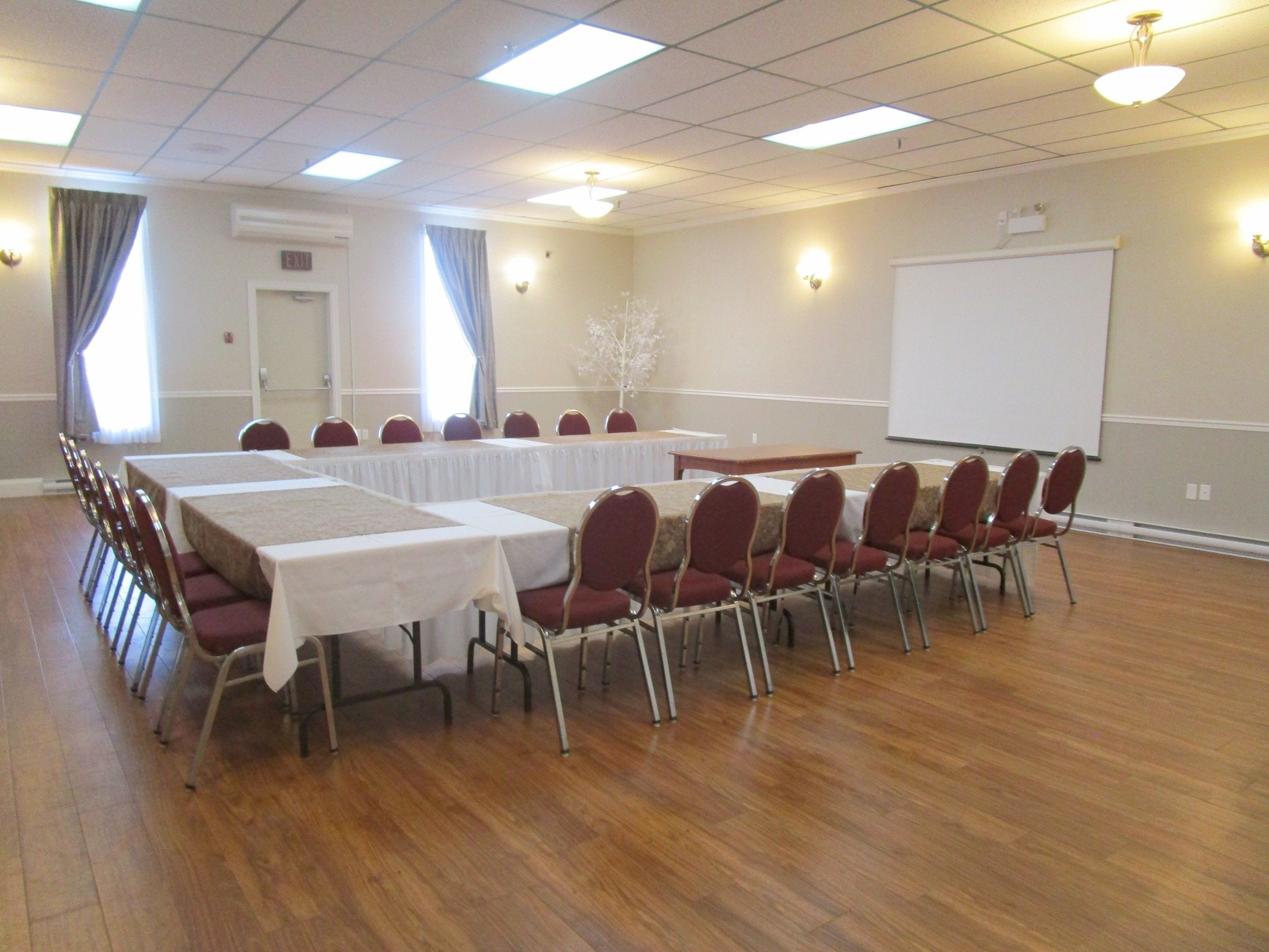 A conference room with tables and chairs, a whiteboard, and a projector screen.